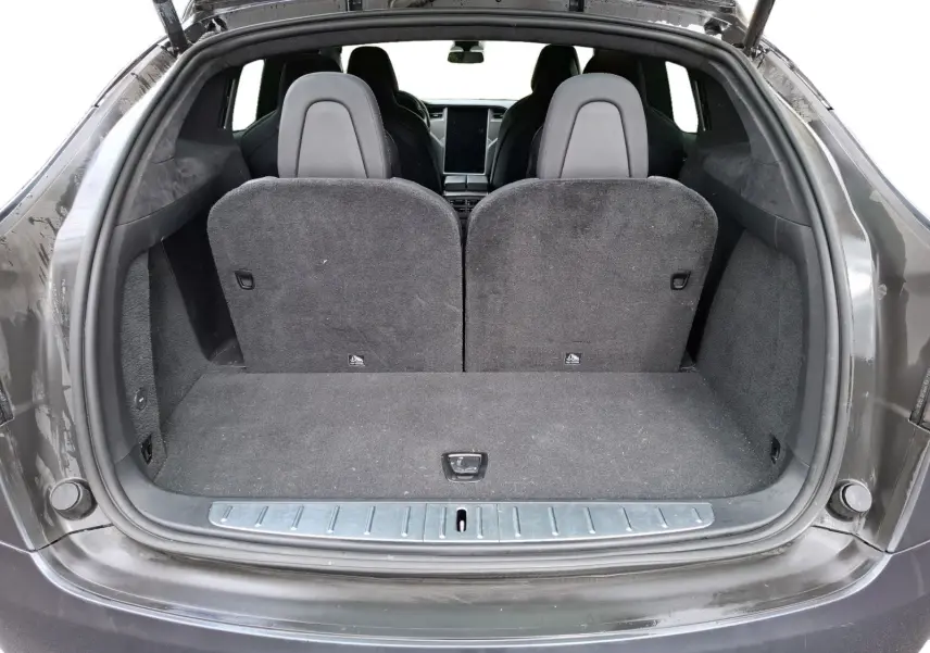 Vue arrière du coffre ouvert d’un Tesla Model X 100D gris foncé, montrant les sièges arrière et l’intérieur spacieux.