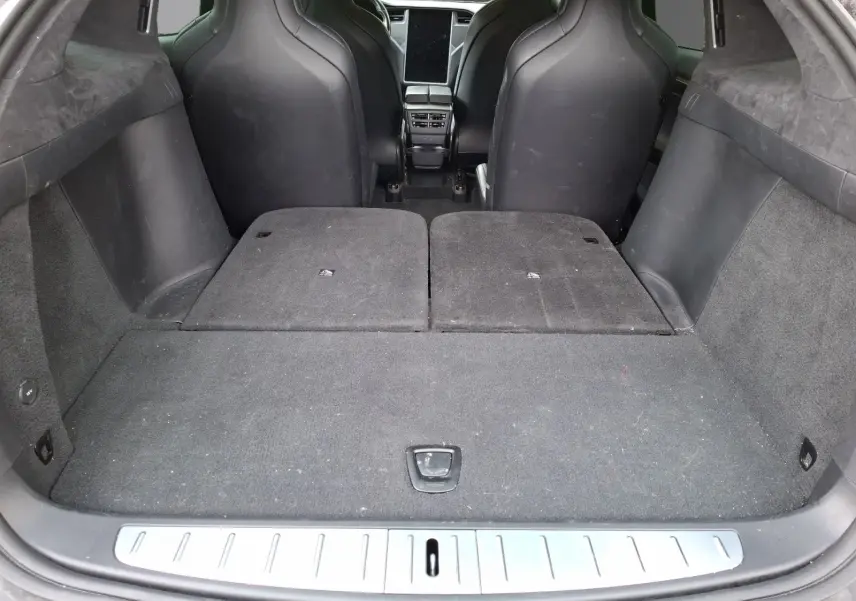 Vue depuis le coffre du Tesla Model X 100D gris foncé, sièges arrière rabattus et espace de chargement plat.