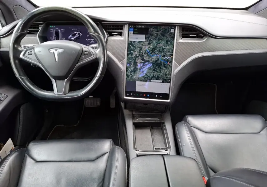 Vue intérieure frontale du tableau de bord de la Tesla Model X 100D 2018 avec écran tactile vertical et volant noir.
