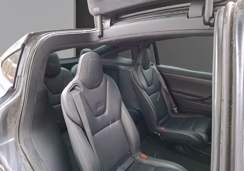 Vue intérieure côté droit du Tesla Model X 100D gris foncé, montrant les sièges en cuir noir et la porte ouverte avec porte-à-faux caractéristique.