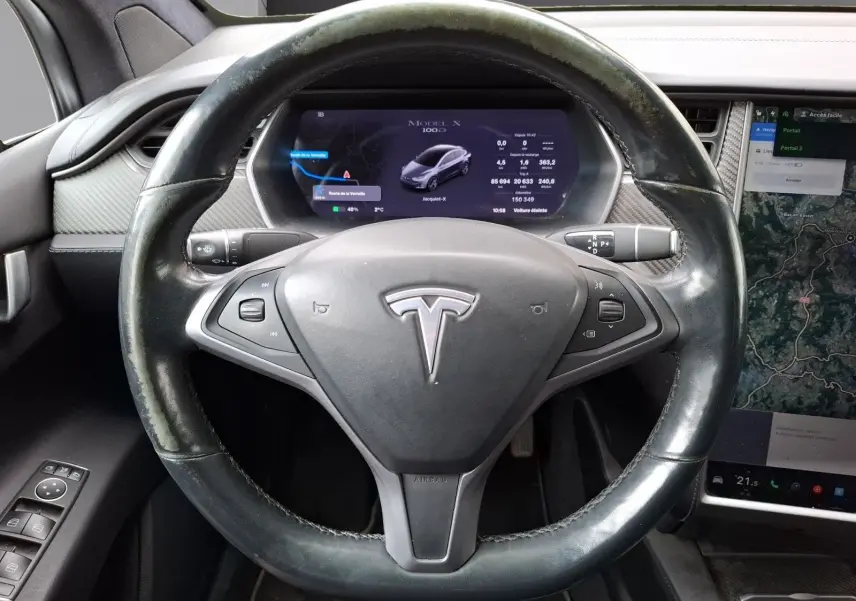 Vue rapprochée du volant noir de la Tesla Model X 100D avec écran numérique et console tactile visible.