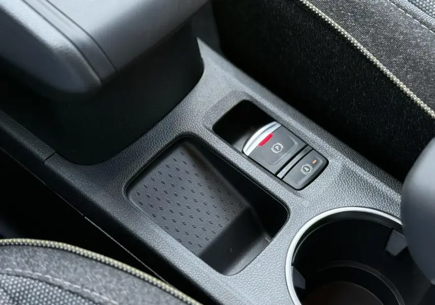 Gros plan sur la console centrale noire du Renault Captur gris Cassiopée, avec frein à main électrique et rangement.