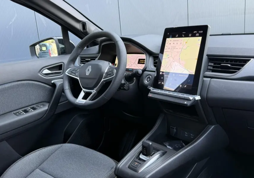 Vue intérieure côté conducteur du Renault Captur gris Cassiopée, avec volant multifonction et grand écran tactile vertical.
