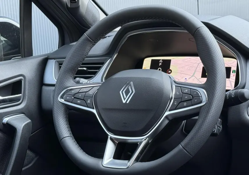 Vue rapprochée du volant noir perforé du Renault Captur 2026 avec tableau de bord numérique et navigation affichée.