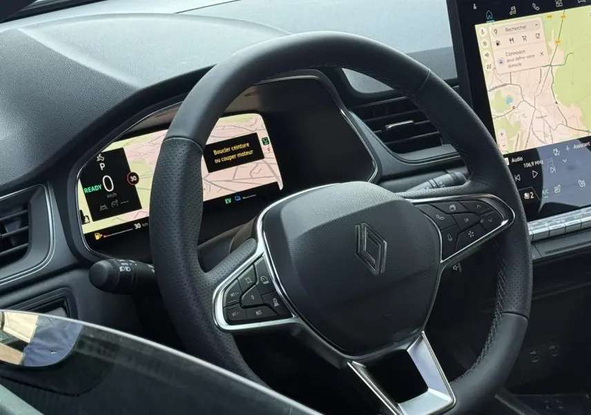 Vue rapprochée du volant noir perforé du Renault Captur 2026 avec tableau de bord numérique et écran tactile central.
