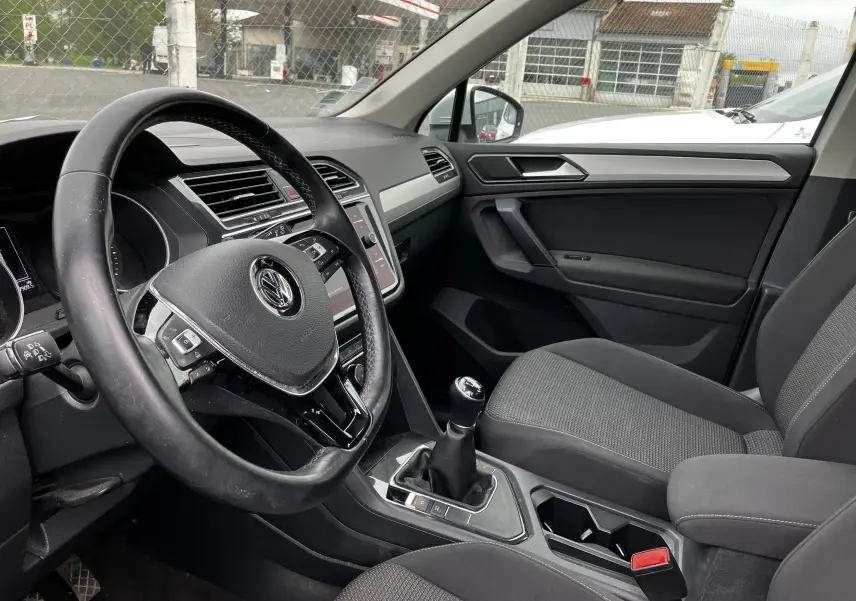 Intérieur côté conducteur du Volkswagen Tiguan blanc 2018, volant multifonctions et levier de vitesse manuel visibles.