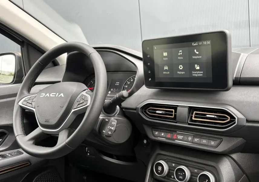 Intérieur de la Dacia Sandero Stepway 2025 en gris, vue de face sur le volant et l'écran tactile central.