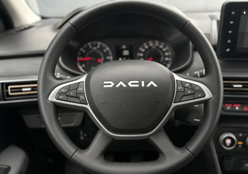 Gros plan sur le volant noir DACIA avec commandes intégrées, tableau de bord et écran tactile du Sandero Stepway 2025.