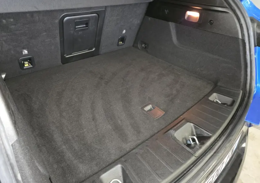 Coffre ouvert vu de dessus d’une Alfa Romeo Tonale bleu 2024, montrant un espace de rangement noir et un éclairage intérieur.