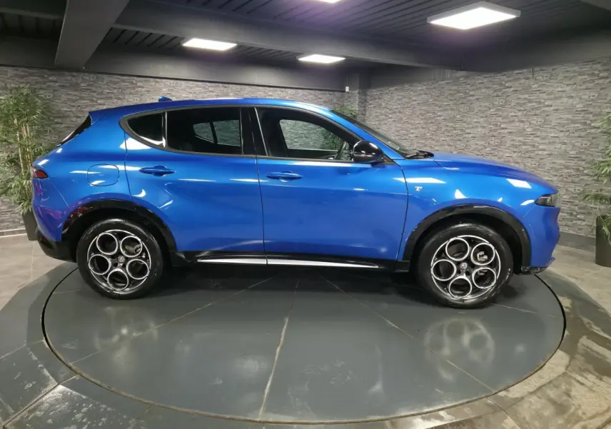 Profil droit d'une Alfa Romeo Tonale 2024 bleu métallisé avec jantes alliage 18 pouces et rétroviseurs noirs brillants.