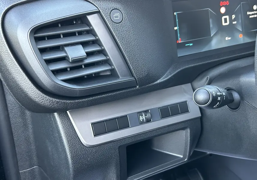 Détail de la console côté gauche du tableau de bord noir du Citroën Jumpy Cabine Approfondie 2025, avec aérateur et commandes.