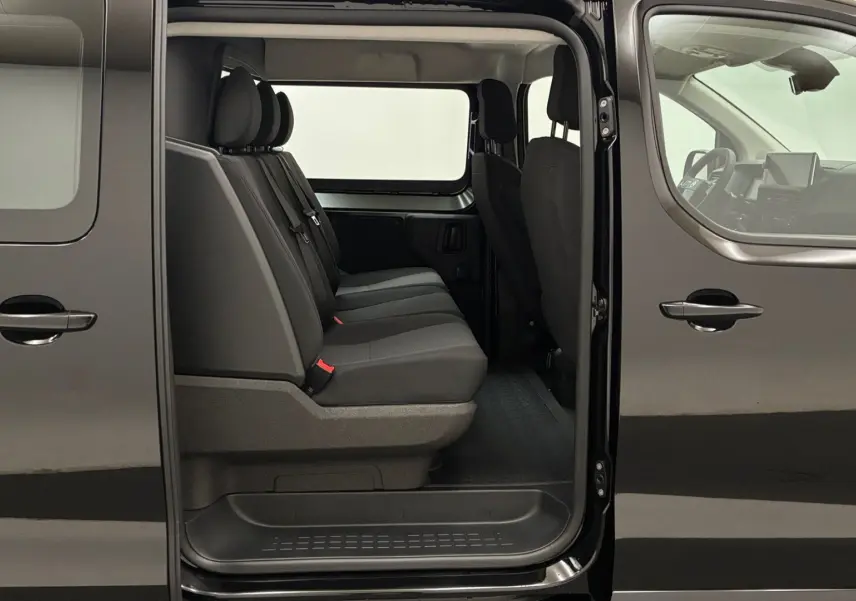 Vue latérale gauche du Citroën Jumpy noir avec porte coulissante ouverte montrant les sièges arrière en tissu gris.