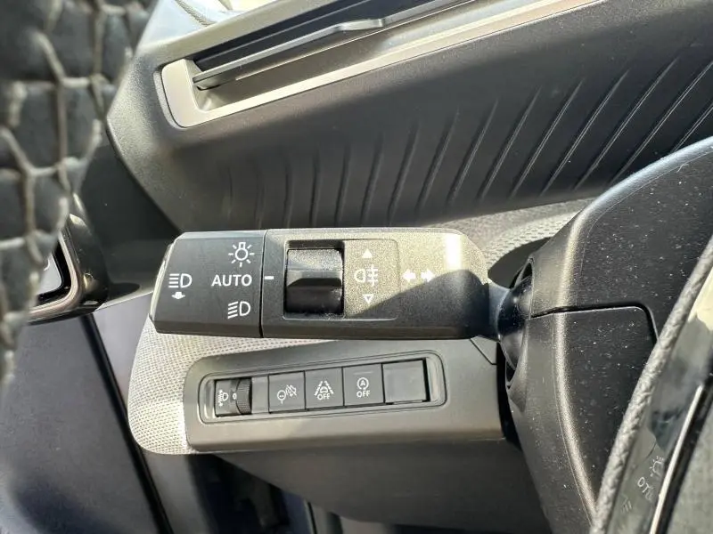 Gros plan sur la commande des phares et des feux antibrouillard à gauche du volant dans l’habitacle gris d’une Citroën C3 2025.