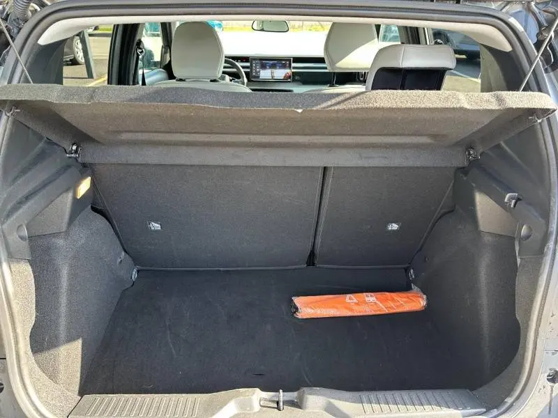 Coffre ouvert vu de l'arrière d'une Citroën C3 gris Mercury 2025, avec un triangle de signalisation orange à l'intérieur.