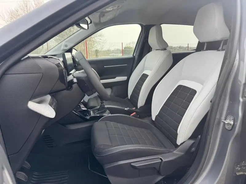 Vue intérieure côté conducteur de la Citroën C3 1.2 Turbo 2025 gris Mercury, sièges bicolores noir et gris avec console centrale.