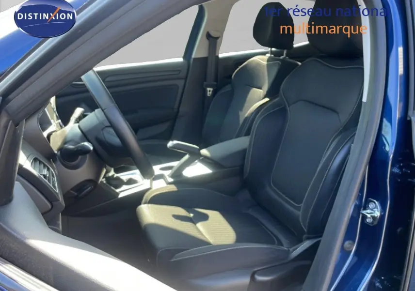 Vue intérieure côté conducteur de la Renault Mégane bleu cosmos, sièges noirs en tissu avec surpiqûres blanches.