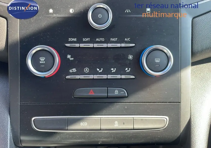 Détail du tableau de bord de la Renault Mégane 2019, montrant les commandes de climatisation avec boutons rotatifs rouge et bleu.