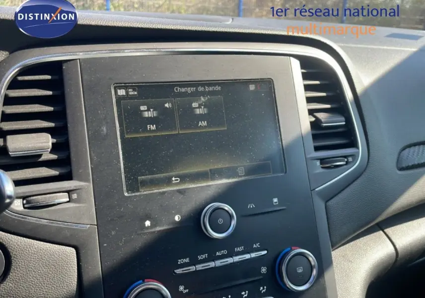Vue rapprochée du tableau de bord de la Renault Mégane 2019, avec écran tactile et commandes de climatisation visibles.