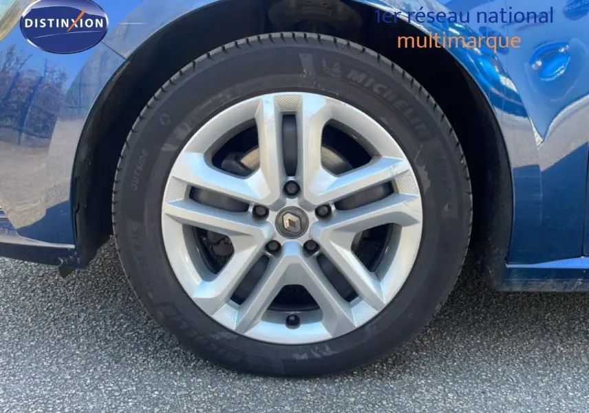 Gros plan sur la roue avant droite d'une Renault Mégane bleu cosmos métal, mettant en valeur la jante alliage et le pneu Michelin.