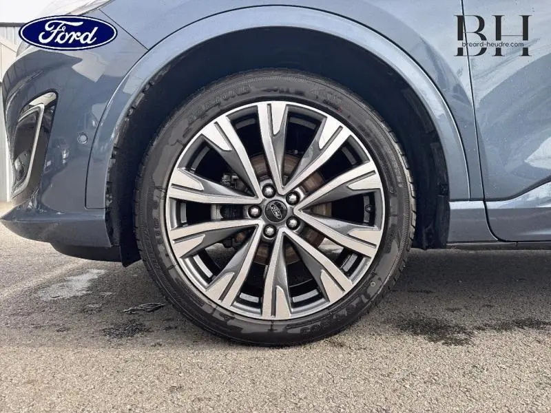 Gros plan sur la roue avant gauche du Ford Kuga bleu azur métallisé avec jante alu 20 pouces à 10 branches.