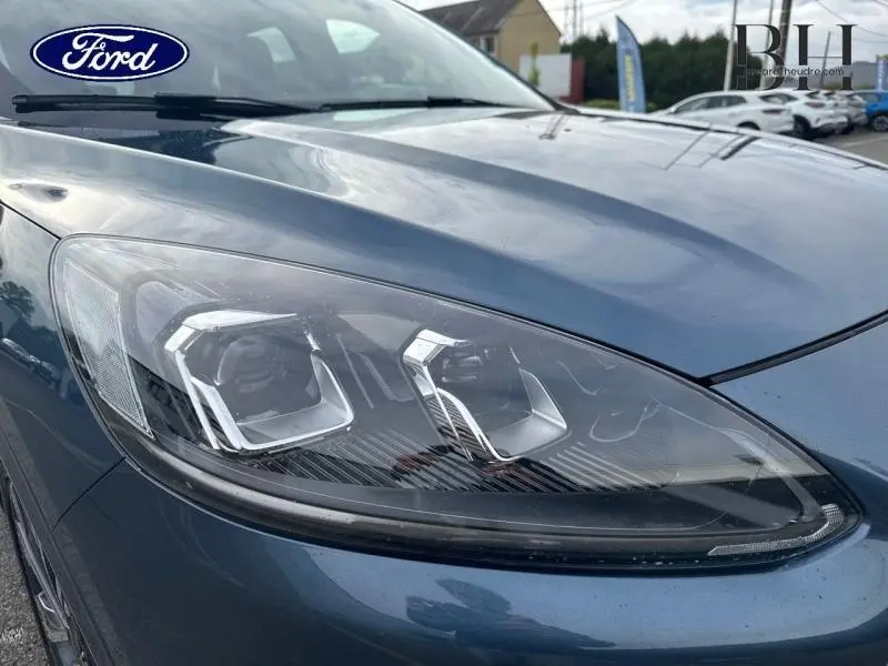 Gros plan sur le phare avant gauche du Ford Kuga 2023 bleu azur métallisé avec détails LED distinctifs.