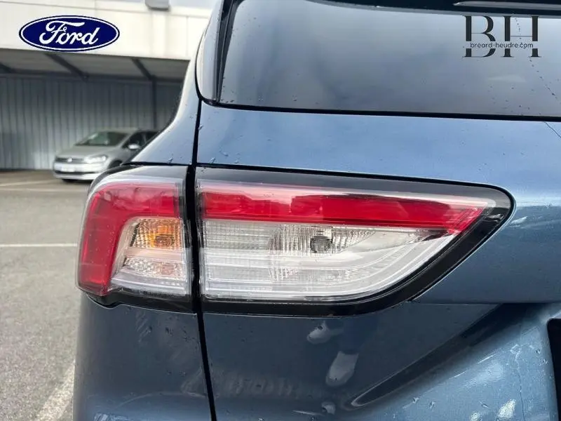 Gros plan sur le feu arrière gauche du Ford Kuga 2023 bleu azur métallisé, soulignant ses lignes modernes et épurées.