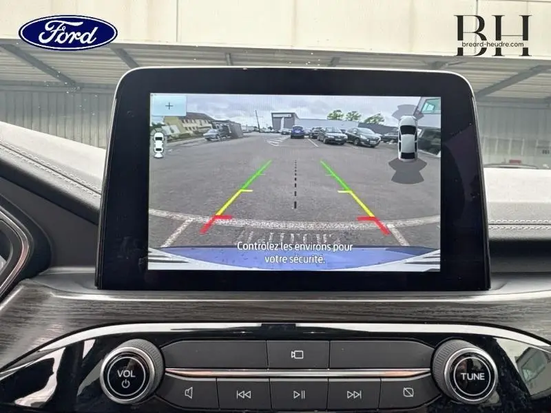 Écran tactile intérieur montrant la caméra de recul du Ford Kuga bleu azur, vue arrière en stationnement.