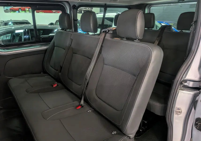 Vue intérieure des sièges arrière en tissu noir du Nissan Primastar Combi gris Highland, avec ceinture de sécurité visible.