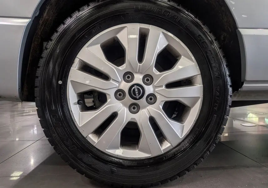 Gros plan sur la roue avant droite du Nissan Primastar Combi gris Highland, jante alliage 17 pouces avec logo Nissan central.