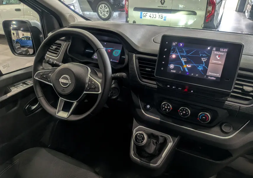Vue intérieure du poste de conduite du Nissan Primastar Combi 2026, avec volant multifonction, écran tactile et levier de vitesses manuel.