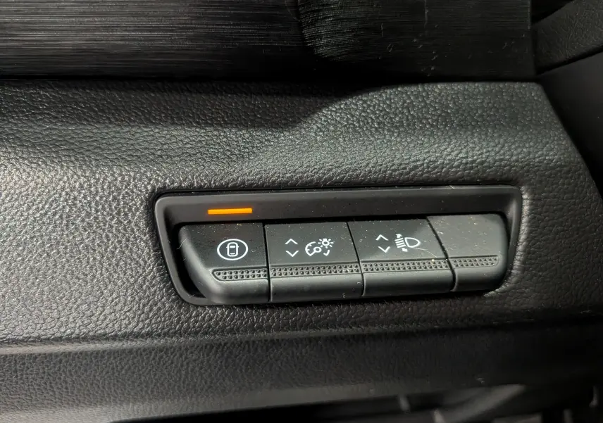 Gros plan sur les commandes de réglage d'éclairage et verrouillage du tableau de bord noir du Nissan Primastar Combi gris Highland.