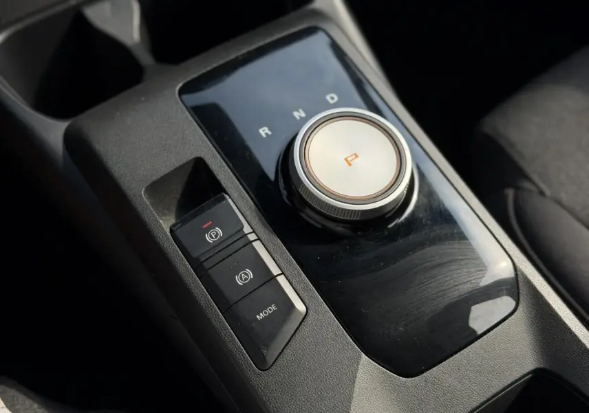 Gros plan sur la commande rotative de boîte automatique et frein électronique dans l’habitacle noir du MG3 2024.