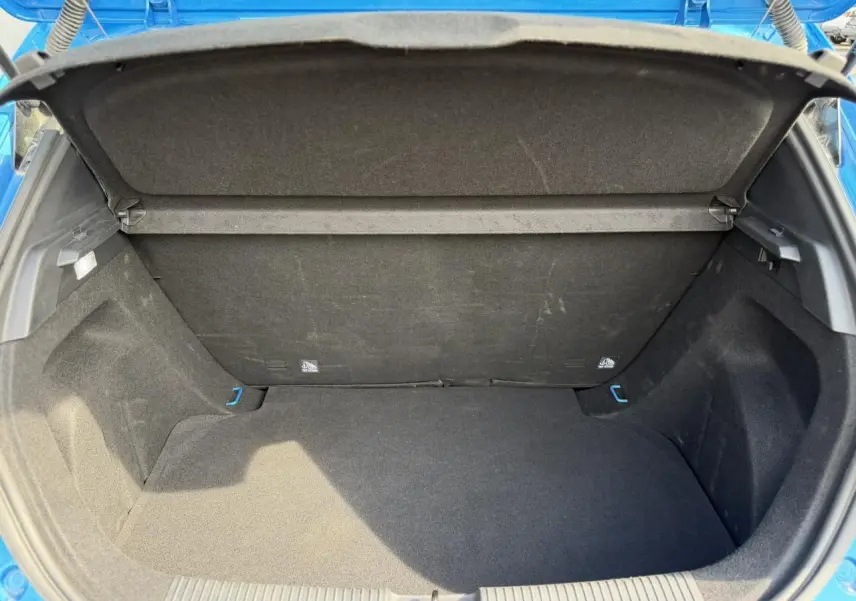 Coffre ouvert vu de l'arrière d'une MG3 1.5 Hybrid+ 195 Comfort bleu Como, intérieur noir et espace de rangement visible.