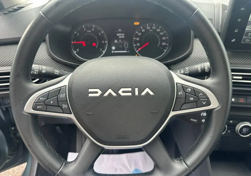 Vue rapprochée du volant noir de la Dacia Jogger 2025 avec commandes intégrées et tableau de bord visible.
