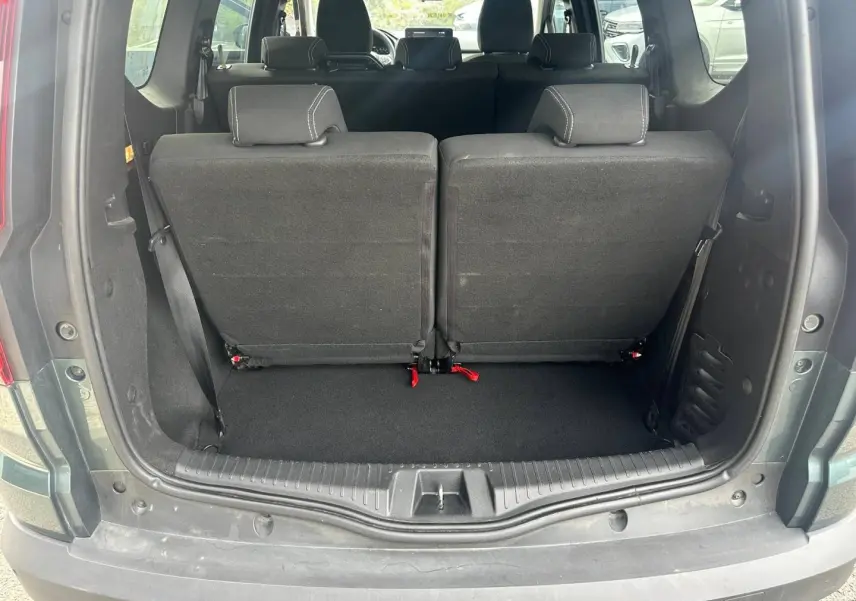 Vue arrière du coffre du Dacia Jogger vert cèdre métallisé avec la troisième rangée de sièges relevée en tissu noir.