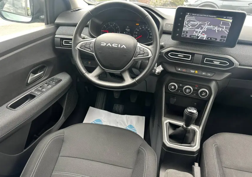 Vue intérieure centrée sur le poste de conduite du Dacia Jogger, volant multifonction et écran tactile visible.