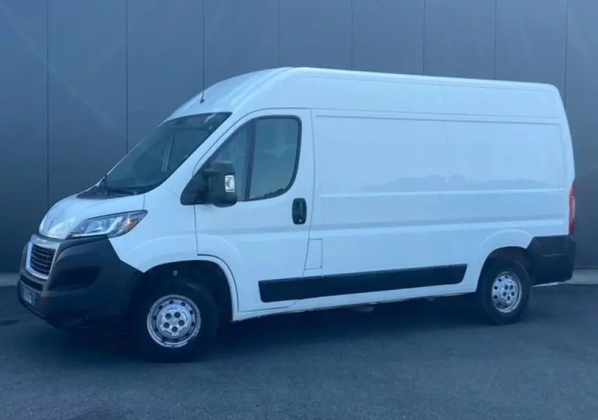 Vue de profil côté gauche d’un Peugeot Boxer Fourgon blanc avec porte latérale coulissante et jantes acier.