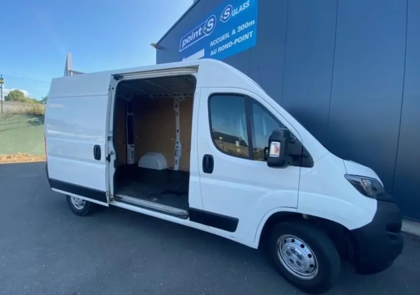 Vue 3/4 avant droit d'un Peugeot Boxer Fourgon blanc 2019 avec porte latérale droite ouverte et intérieur utilitaire visible.