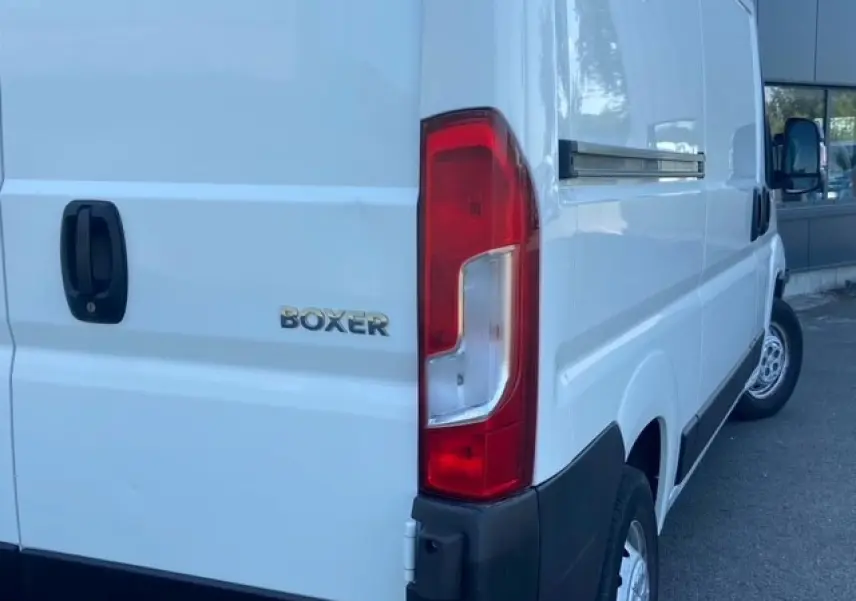 Vue arrière droite du Peugeot Boxer Fourgon blanc montrant le feu arrière et le logo BOXER sur la porte.