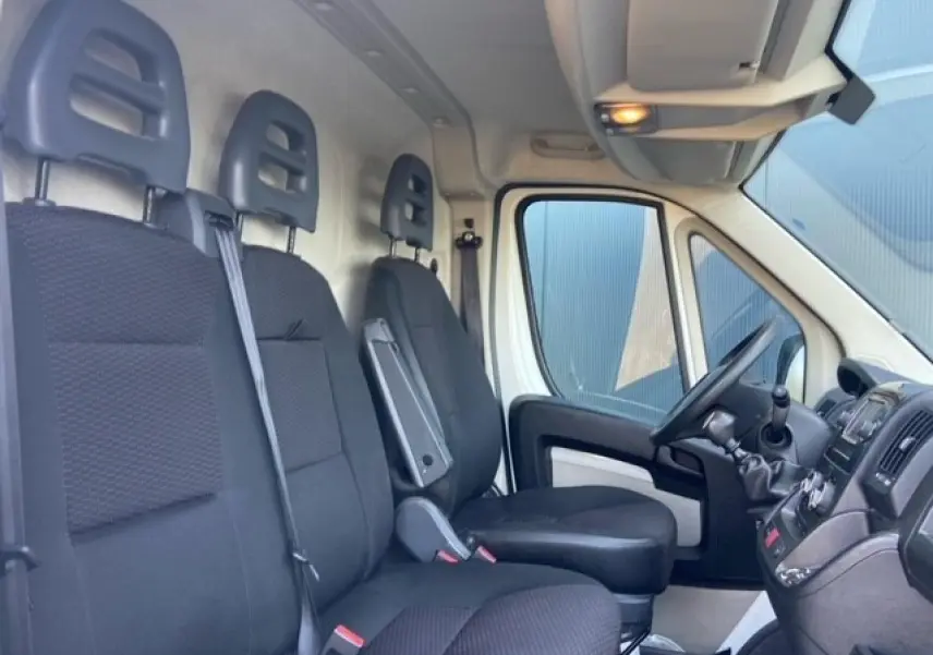 Intérieur du Peugeot Boxer Fourgon 2019 vu côté droit, montrant les sièges noirs et le tableau de bord avec boîte manuelle.