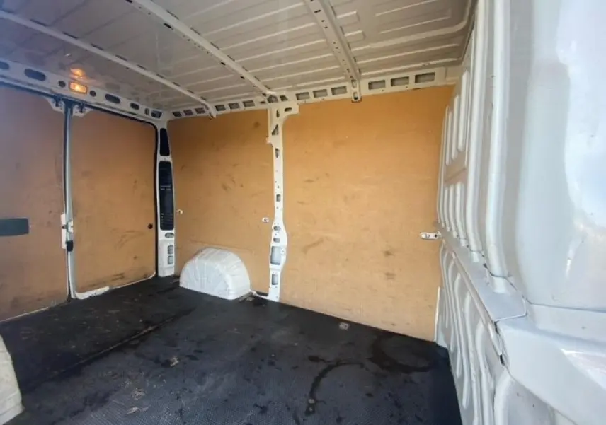 Intérieur du fourgon blanc Peugeot Boxer III 330 L2H2, vue vers l'arrière avec parois en bois et sol noir.
