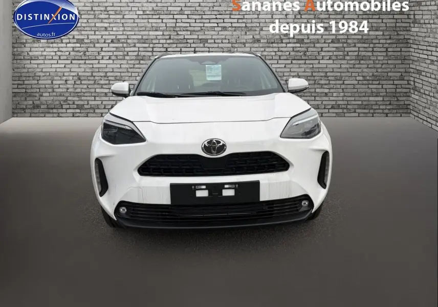 Vue frontale d'une Toyota Yaris Cross Hybrid 130h blanche, avec calandre noire et phares LED marqués.