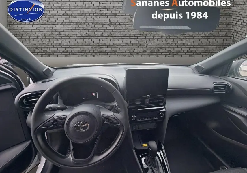 Vue intérieure avant de la Toyota Yaris Cross Hybrid 130h 2025, tableau de bord noir avec écran tactile central.