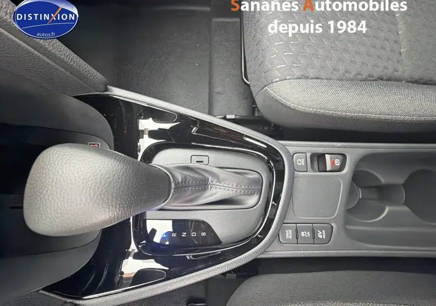 Vue plongeante sur le levier de vitesses automatique et la console centrale noire de la Toyota Yaris Cross Hybrid 130h blanche.