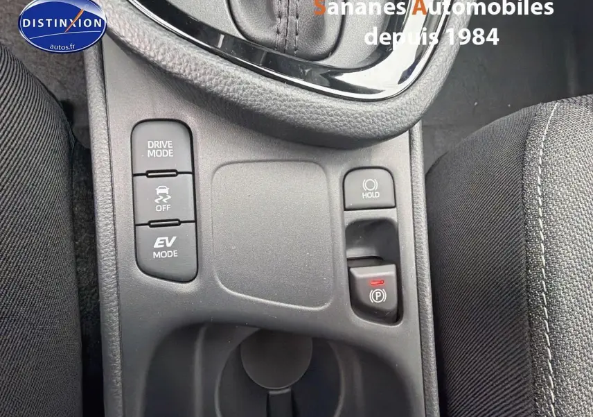 Vue rapprochée du panneau de commandes central de la Toyota Yaris Cross Hybrid 130h blanc, avec boutons Drive Mode et frein de parking électronique.