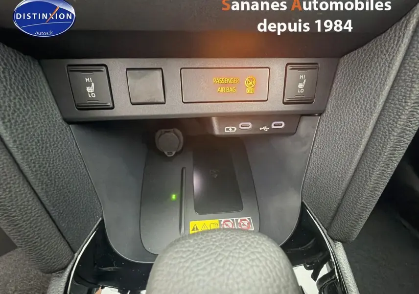 Gros plan sur la console centrale avec commandes sièges chauffants et ports USB d'une Toyota Yaris Cross blanche hybride 2025.