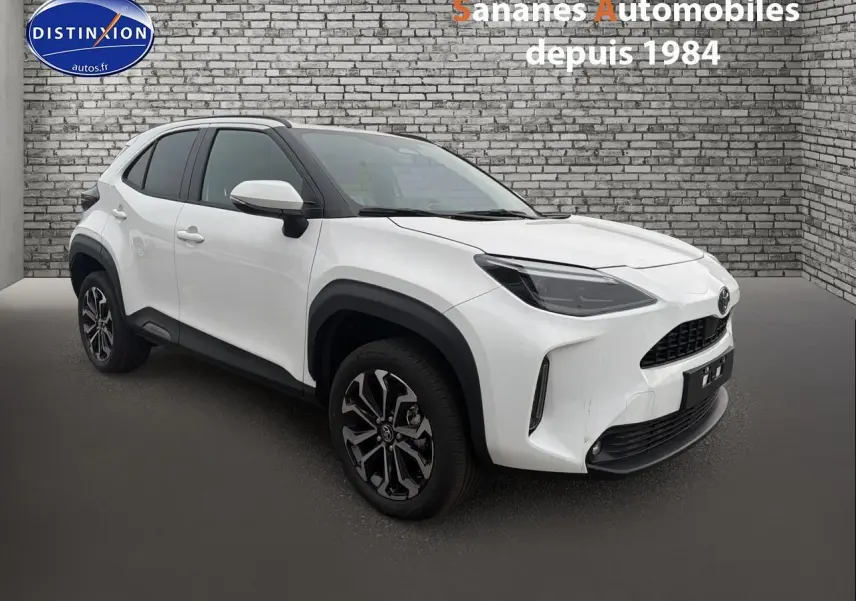 Toyota Yaris Cross hybride blanc en 3/4 avant droit, avec jantes alliage et protections noires autour des roues.