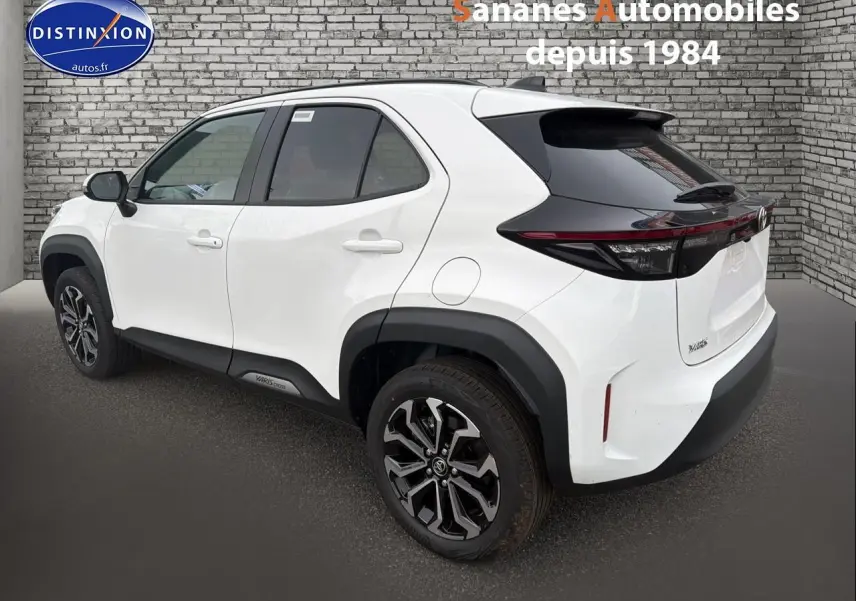 Vue 3/4 arrière droite de la Toyota Yaris Cross Hybrid 130h blanche avec jantes alliage et toit noir contrasté.