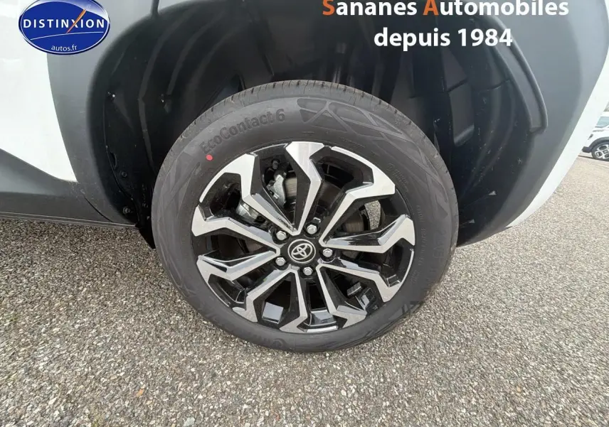 Gros plan sur la jante alliage noire et argentée côté arrière droit de la Toyota Yaris Cross blanche 2025.