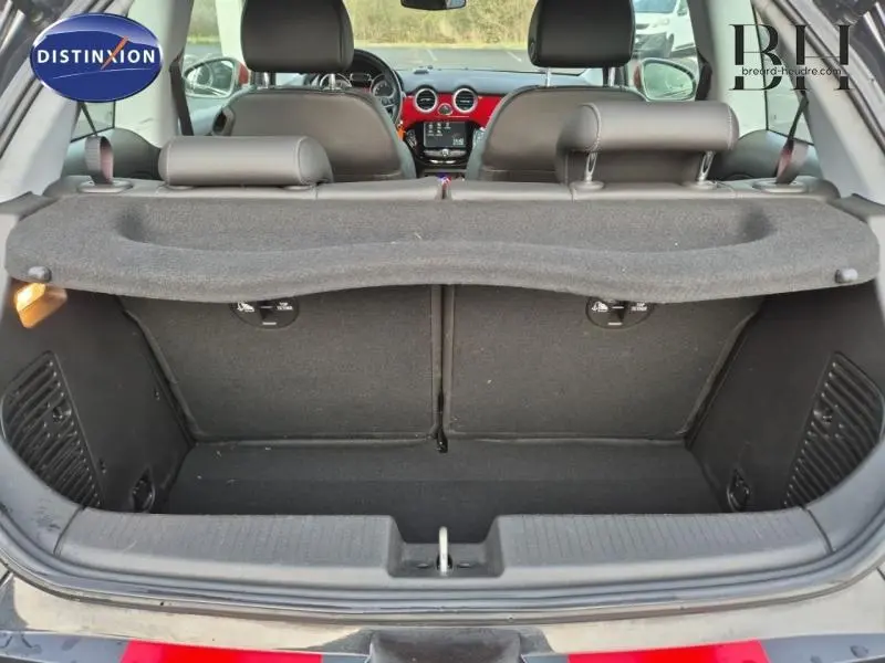 Vue arrière du coffre ouvert d'une Opel Adam Rocks noire, avec banquette arrière et tableau de bord visibles.
